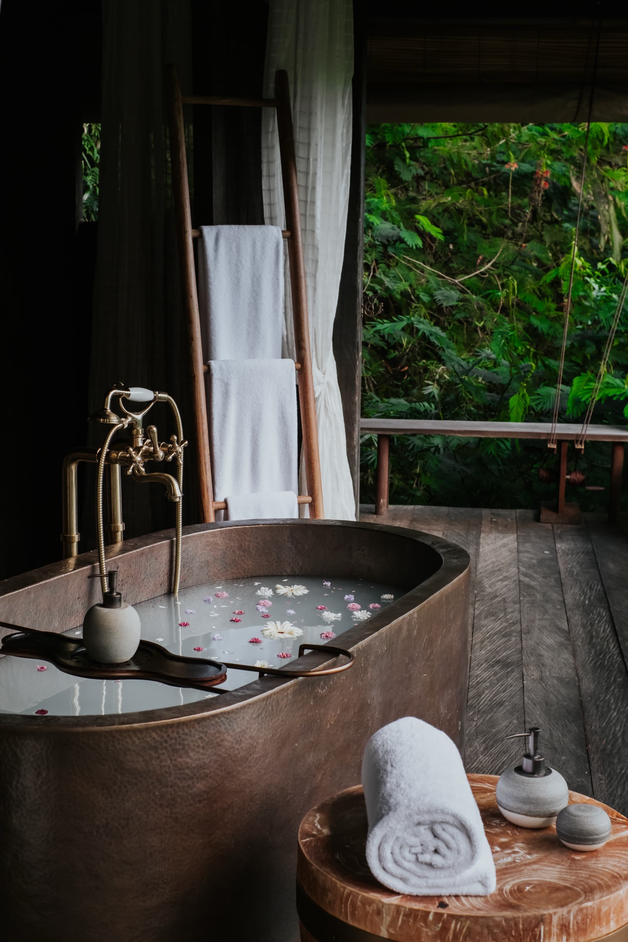 Open-air villa bathroom with copper soaking tub facing the forest