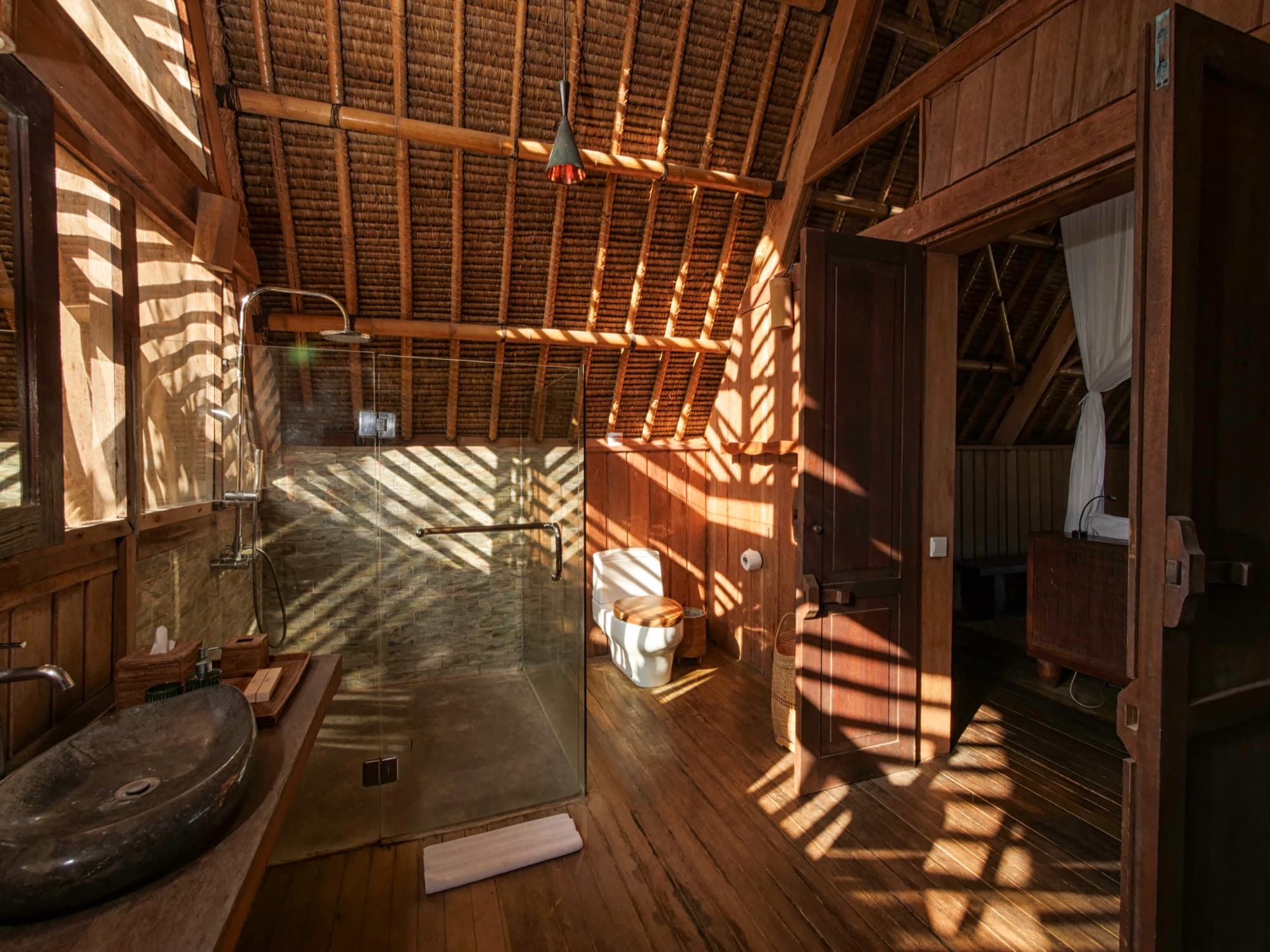 Open-air lodge bathroom with timber finishes at Jeeva Beloam Beach Camp, Lombok
